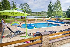 a pool with a green umbrella and people in it at Rezydencja nad jeziorem Pestkownica in Pestkownica