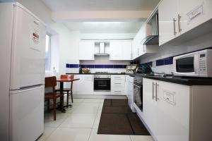 una cocina con electrodomésticos blancos y una mesa. en Flexistay Aparthotel Sutton en Sutton