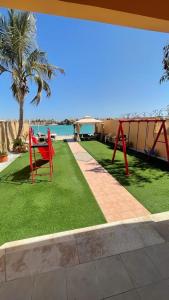 a patio with a red table and chairs on the grass at فيلا بمسبح خاص درة العروس in Durat Alarous