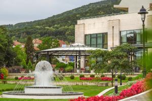 a fountain in a park in front of a building at A Hoteli - Hotel Izvor in Arandelovac