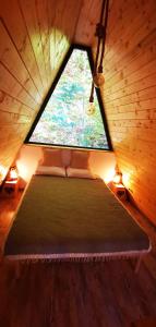 uma cama num quarto com uma grande janela em Casa - Cabana Tip A Frame, Cerna, Vaideeni, Valcea em Cerna