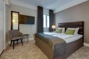 a bedroom with a bed and a chair and a television at Clarion Collection Hotel Victoria in Jönköping