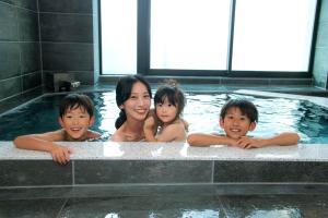 Una donna e tre bambini in una vasca idromassaggio di ＥＮＴ　ＴＥＲＲＡＣＥ　ＡＳＡＫＵＳＡ a Tokyo