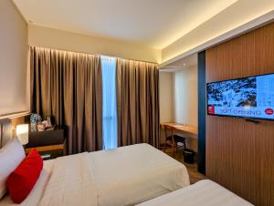 a hotel room with two beds and a flat screen tv at Grand Zuri Lubuklinggau in Lubuklinggau