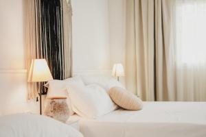 - une chambre avec un lit blanc avec des oreillers et une fenêtre dans l'établissement Drymades Bungalows Adults Only, à Dhërmi