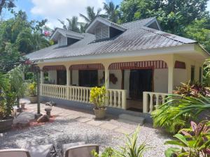 a house with a white fence and a porch at Domaine Les Rochers in La Digue