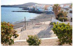 uma vista para uma praia com um banco e para o oceano em Casa Laura y Pancho em Fasnia