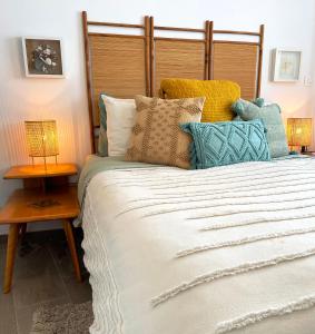 een slaapkamer met een groot bed met kleurrijke kussens bij Great outdoor living steps away from the beach in Sutivan