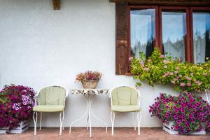 two chairs and a table in front of a building with flowers at Ostoja Wigierski in Mikolajewo