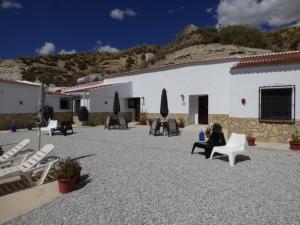 eine Terrasse mit Stühlen und Sonnenschirmen vor einem Gebäude in der Unterkunft Cave Holidays Andalucia in Los Carriones