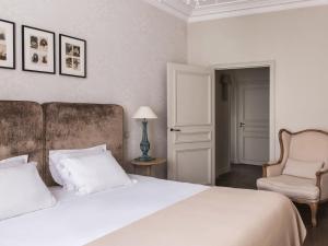 um quarto com uma grande cama branca e uma cadeira em New Hotel Roblin em Paris