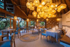 a dining room with tables and chairs and chandeliers at Thonga Beach Lodge in Mabibi