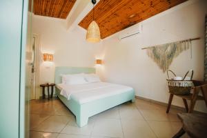 a bedroom with a white bed and a wooden ceiling at Drymades Bungalows Adults Only in Dhërmi