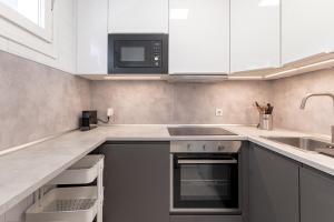 a kitchen with white cabinets and a sink and a microwave at Bakio Seaview V by Aston Rentals in Bakio