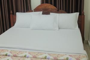 een groot bed met witte lakens en kussens bij Corina K Guest House in Kigali