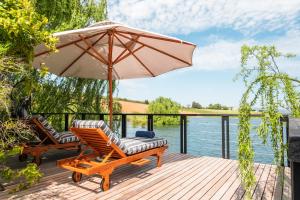 two chairs and an umbrella on a deck next to the water at Ladybird Lodge in Stellenbosch