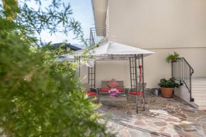 un patio con una sombrilla blanca y un banco en L'antica corte apt Mara, en Levico Terme