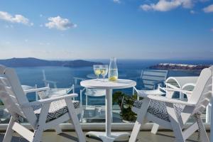 een tafel en stoelen op een balkon met uitzicht op de oceaan bij Andromeda Villas & Spa Resort in Imerovígli