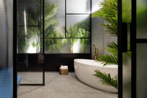 a bathroom with a bath tub and a plant at Muralla Sevilla Suites By Lola in Seville