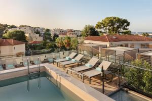 a swimming pool with lounge chairs on top of a building at The 1932 Hotel & Spa Cap d'Antibes - MGallery Collection in Juan-les-Pins