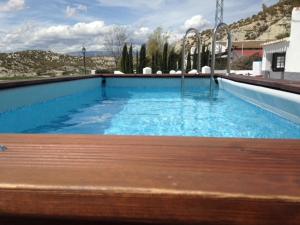 ein Pool mit einer Holzbank davor in der Unterkunft Cave Holidays Andalucia in Los Carriones