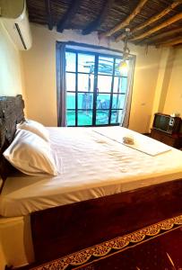 a large bed in a room with a window at ROSES HOUSE OMAN 2 in Al ‘Aqar