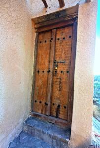 une porte en bois sur le côté du bâtiment dans l'établissement ROSES HOUSE OMAN 2, à Al ‘Aqar
