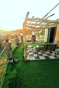 un patio avec deux bancs sous une pergola dans l'établissement ROSES HOUSE OMAN 2, à Al ‘Aqar