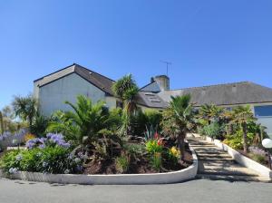 a house with palm trees and flowers in a driveway at KER-AR-MOR Village Vacances in Le Pouldu