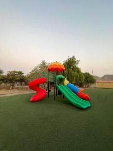 a playground with colorful slides and an umbrella at The Fort Farm in Suḩaybah