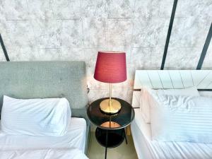 a red lamp on a table next to two beds at E 1-5Pax Cozy home 4 Bed Wifi TV Trefoil @Setia City Setia Alam SCCC in Setia Alam