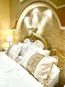 a bedroom with a white bed with a gold headboard at Roza Luxury Apartment in Budapest
