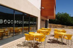 a row of yellow tables and chairs outside of a building at HI Alvados - Pousada de Juventude in Alvados