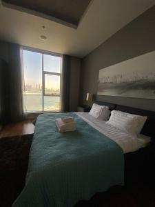 una camera da letto con un grande letto con una grande finestra di Tiara Emerald - 1BR Apartment - Allsopp&Allsopp a Dubai