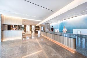 un hall d'un immeuble avec des personnes debout à un comptoir dans l'établissement Atour Hotel Lianyungang Municipal Affairs Central University Town, à Lianyungang