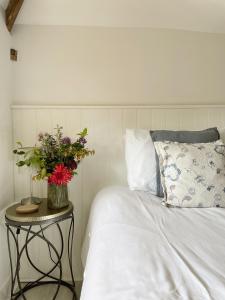 a bedroom with a bed and a table with a vase of flowers at The Granary, Norfolk in Norwich