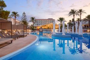 una piscina de hotel con palmeras y un edificio en Meliá Zahara Resort & Villas, en Zahara de los Atunes