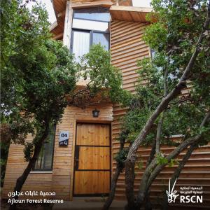 a wooden house with a wooden door and trees at Ajloun Forest Reserve in Jerash