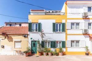 a building with green shuttered windows and potted plants at Vita Portucale ! Costa Caparica Triplex w/ Terrace in Costa da Caparica