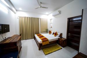 1 dormitorio con 1 cama y TV en Mojo M Villa -Airport Boutique Hotel, en Jaipur