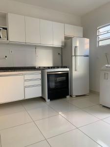 a kitchen with white cabinets and a refrigerator at CASA DE TEMPORADA in Aracaju