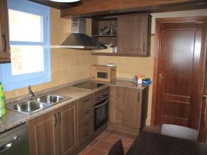 cocina con armarios de madera, fregadero y ventana en Ca de Costa, en El Pont de Suert