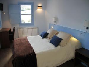 a bedroom with a white bed with blue pillows at Ca de Costa in El Pont de Suert