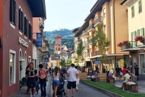 un gruppo di persone che camminano per una strada con edifici di CASA BEBA - Cavalese Olimpiadi 2026 Dolomiti Affitti a Cavalese