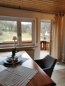 ein Esszimmer mit einem Tisch und zwei Fenstern in der Unterkunft Ferienwohnung am Bach in Mörlenbach