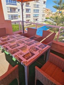 een tafel op een balkon met stoelen en een parasol bij Magnifico chalet adosado en Torrevieja, Alicante. in Torrevieja