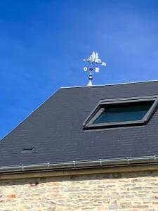 een zwart dak met een raam en een windwijzer bij LA VELOGIROUETTE in Feuguerolles-sur-Orne