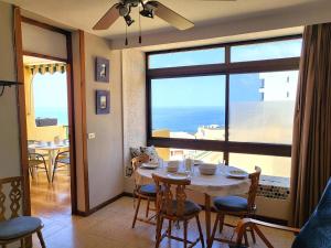 a dining room with a table and a view of the ocean at Sunset Arena Beach by HelloApartments in Puerto de Santiago