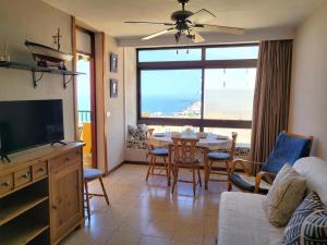 a living room with a television and a table with chairs at Sunset Arena Beach by HelloApartments in Puerto de Santiago