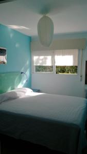 a bedroom with a white bed and two windows at Casita in Madrid